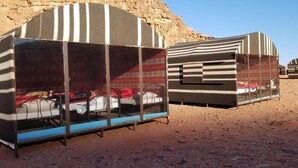 Two striped, enclosed tents with metal frames and glass panels, set in a desert environment with rocky terrain. - Wadi Rum Desert Camp (Wadi Rum)
