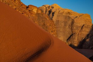 A desert landscape with sand dunes and rock formations. - Wadi Rum Desert Camp (Wadi Rum)