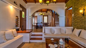 Ein gemütliches Wohnzimmer mit einer Couch, einem Couchtisch und einer Treppe, die in einen Essbereich führt.