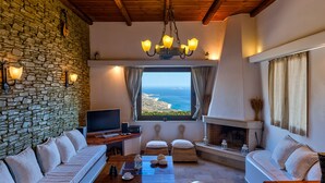 Ein gemütliches Wohnzimmer mit Steinwand, Kamin und Meerblick.