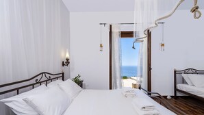 Ein Schlafzimmer mit Bett, Nachttisch, Pendelleuchte und Meerblick.
