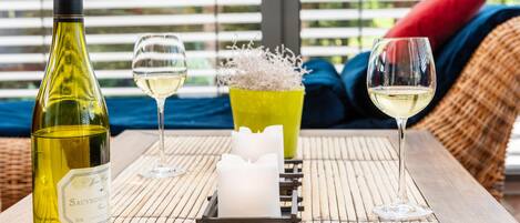 Una botella de vino sauvignon, dos copas de vino, una vela y un candelabro decorativo sobre una estera de bambú.