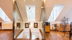 A modern interior with a glass partition, wooden flooring, and a loft-style ceiling.