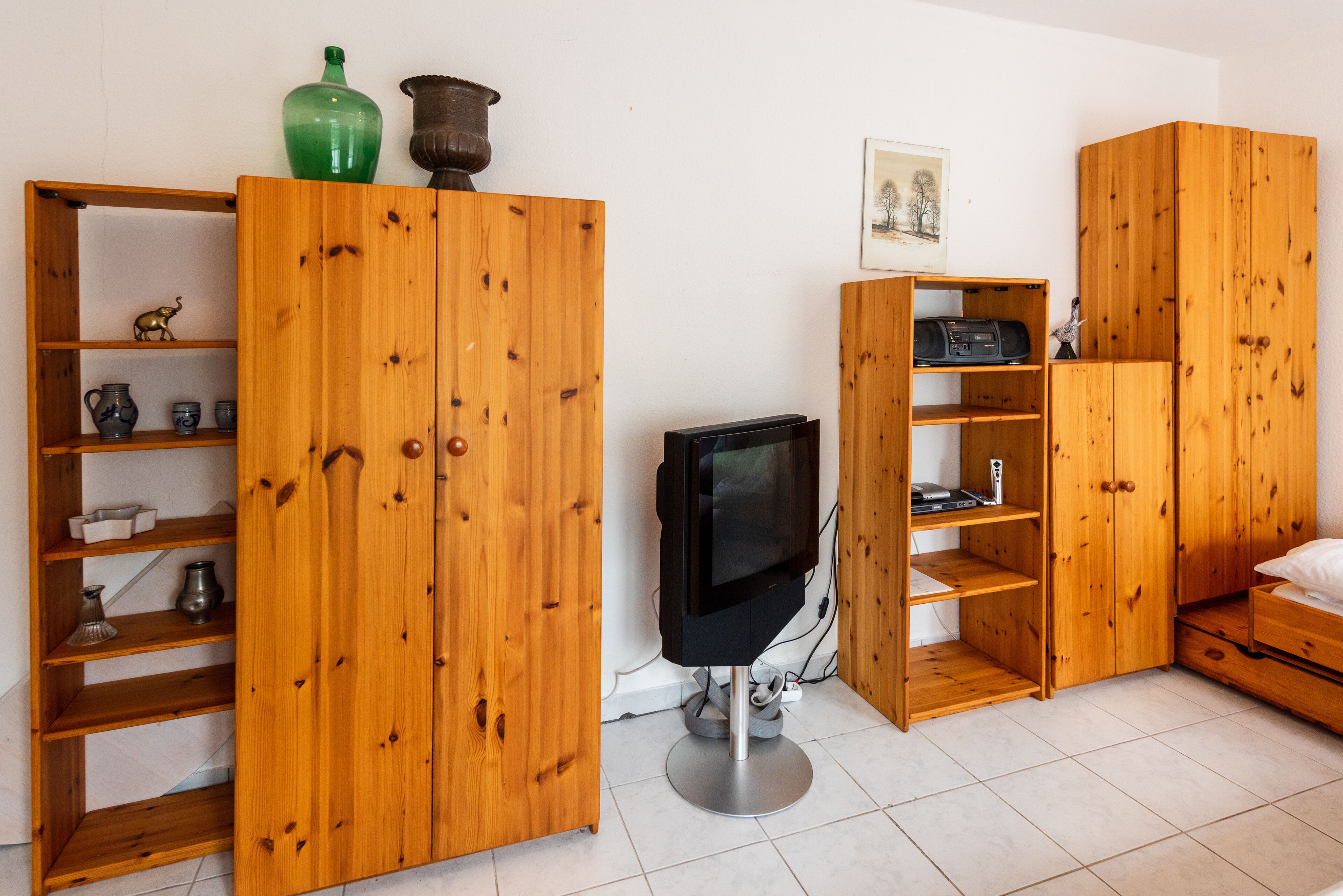 A room with wooden furniture, including a TV stand, shelves, and a cabinet.