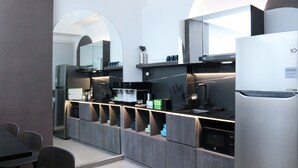 Une cuisine moderne équipée d’un réfrigérateur encastré, d’une machine à café et d’un coin repas avec une table et des chaises.