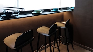 A kitchen area with a window, a sink, and two bar stools. - ST Signature Bugis Beach (Singapore)