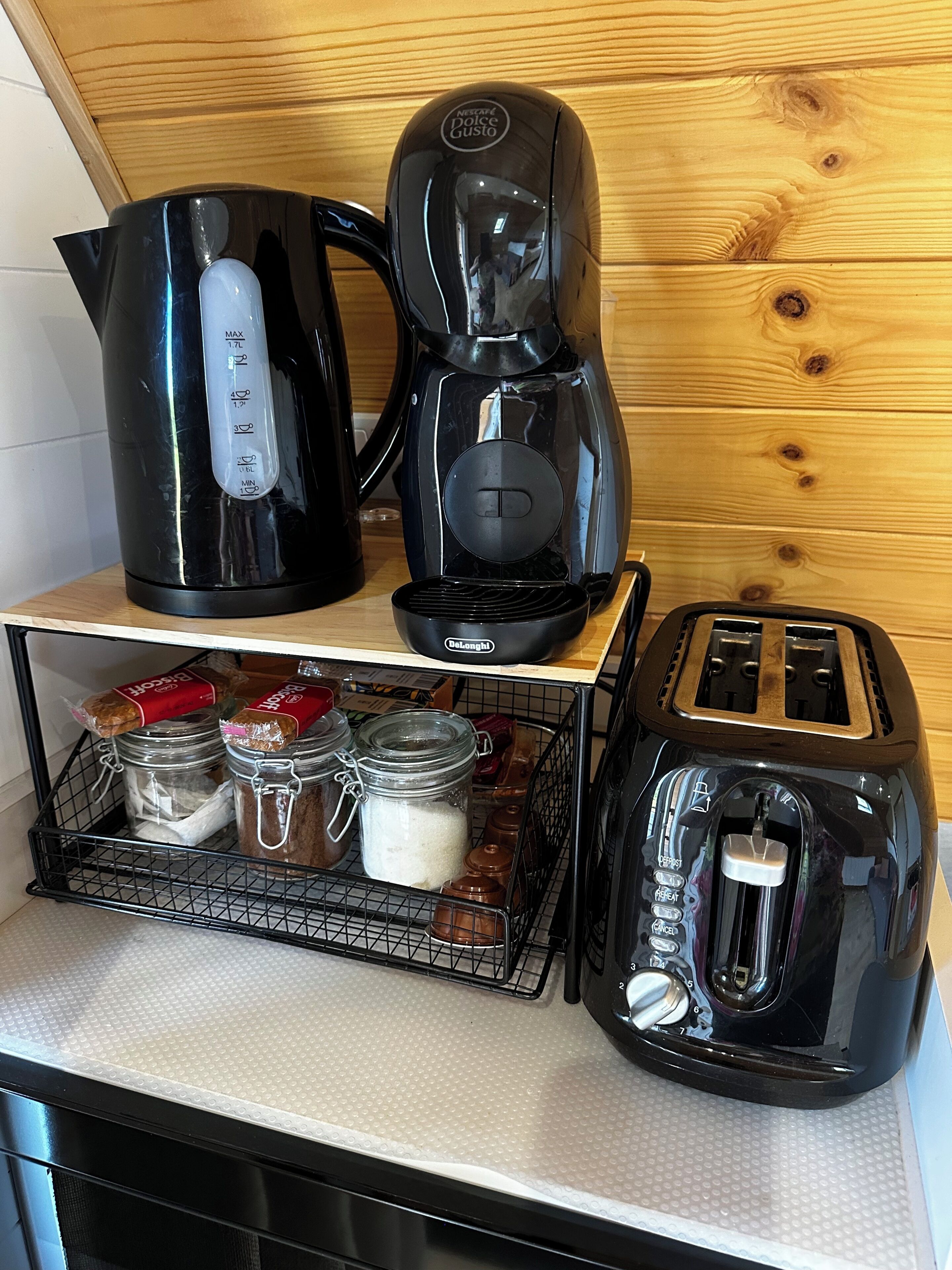 A kitchenette with a coffee maker, toaster, and jars of food on a countertop.