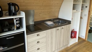 Una cocina compacta con microondas, hervidor y fregadero.