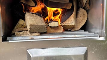 Un poêle à bois avec des bûches et des flammes à l’intérieur.