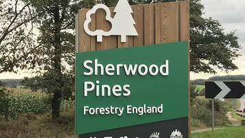 A sign for Sherwood Pines Forestry England with symbols for cycling, a coffee cup, and camping.