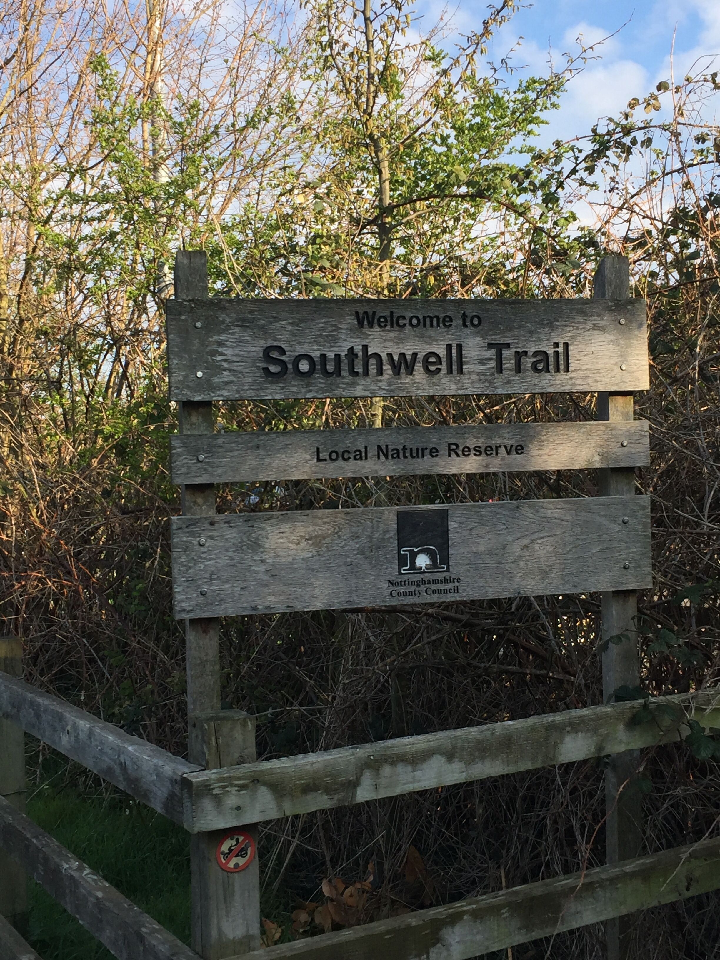 A wooden sign welcoming visitors to Southwell Trail, indicating it is part of a local nature reserve managed by Nottinghamshire County Council.