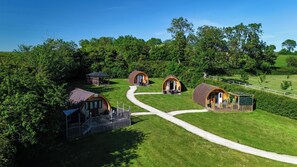 A rural property with four wooden cabins, a gazebo, and a fenced area with a pathway.
