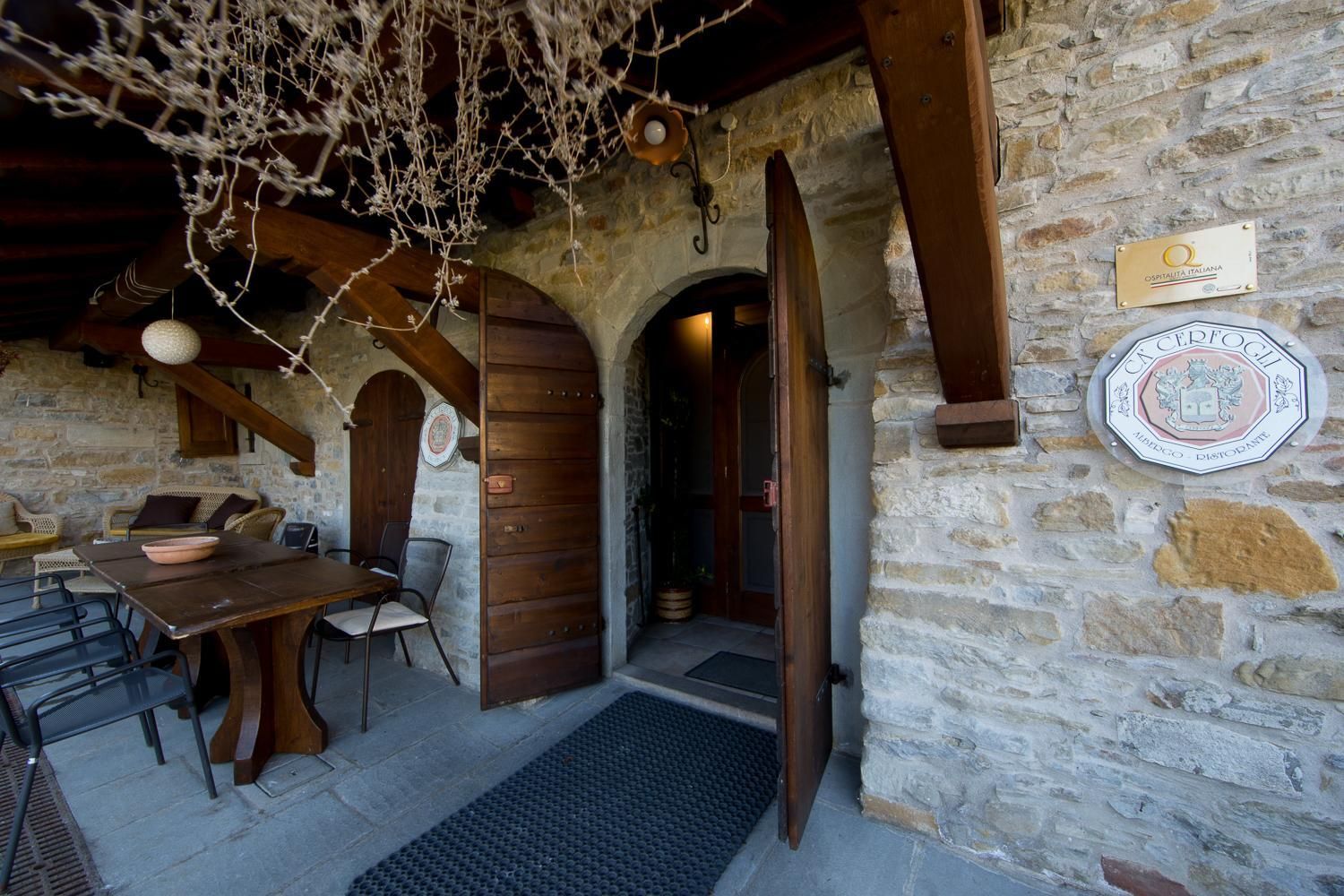 Ein Steinhaus mit einem Holztisch und Stühlen draußen, einer Tür und einem Schild an der Wand.
