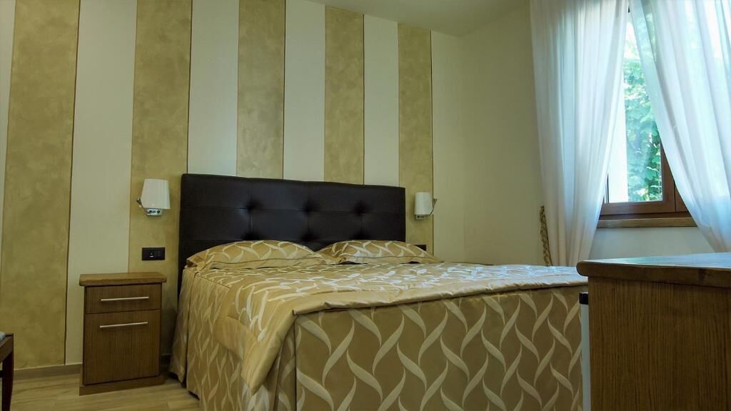 A bedroom with a bed, bedside tables, and a window with curtains.