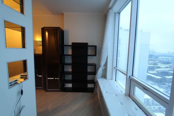 Enjoy a city view from the large window in this cozy room, featuring a shelving unit and a radiator.