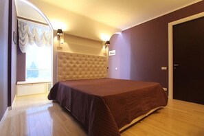 Cozy retreat with a large bed, tufted headboard, and wall-mounted lighting.