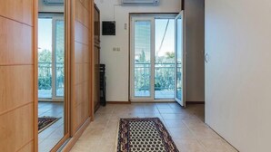 Un pasillo con puertas correderas que dan a un balcón, suelo de baldosas y alfombra estampada.