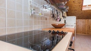 Una cocina con estufa negra, encimera de madera y un colgador para ollas.