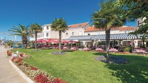 Un patio con mesas al aire libre, palmeras y un edificio con toldos a rayas.