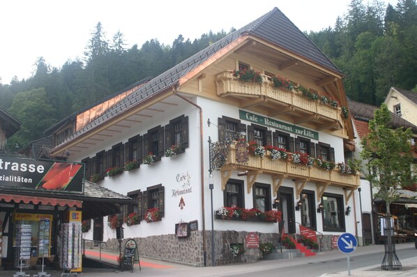 A traditional European building with a restaurant sign, wooden balconies, and flower boxes.