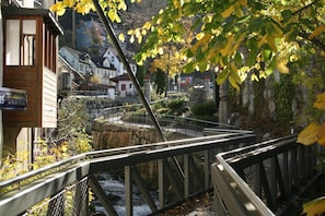 A wooden building with a sign, a metal bridge with a railing, and a stone structure in the background.