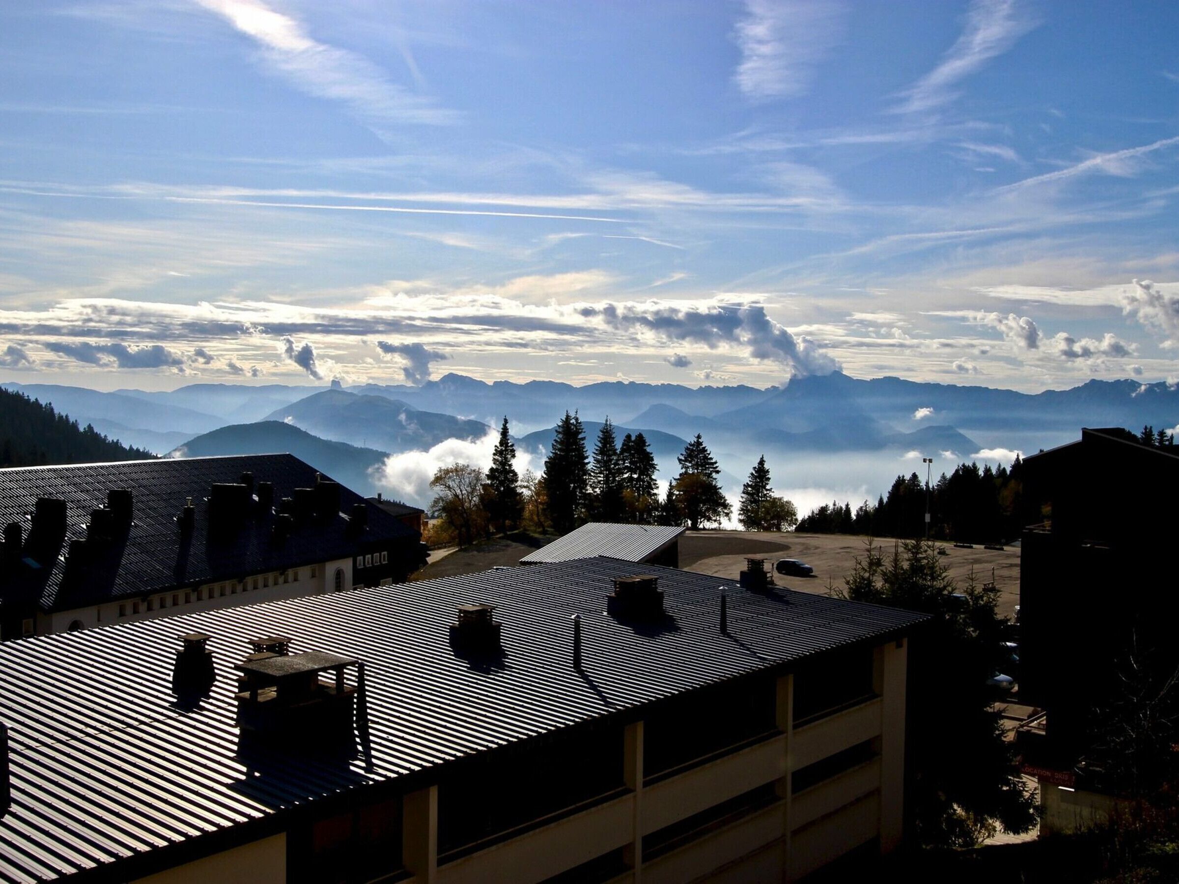 A building with a sloped roof and a view of distant mountains.