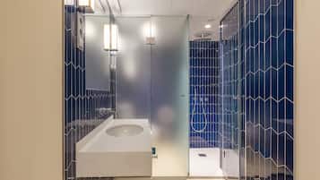 A modern bathroom with a glass shower enclosure, a white sink, and a mirror.