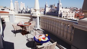 A rooftop terrace with a table set for two, overlooking a cityscape with various buildings. - Room Mate Macarena, Madrid Gran Vía (Madrid)