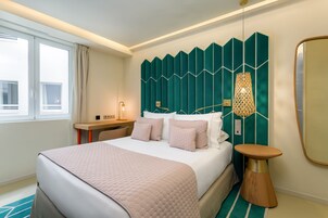 Ein modernes Hotelzimmer mit einem großen Bett, einem Nachttisch, einer Lampe und einem Spiegel.