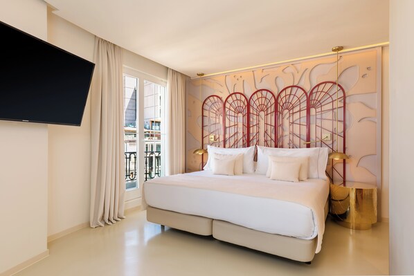 Una habitación de hotel moderna con una cama grande, un televisor de pantalla plana montado en la pared y un balcón con vistas a edificios.