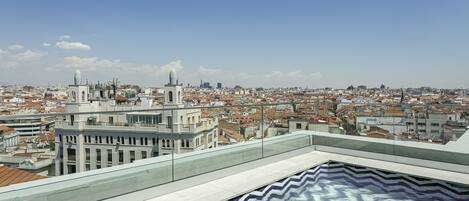 Terraza en la azotea con vistas panorámicas de la ciudad, con edificios modernos y cielo despejado.