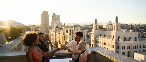 Un grupo de personas en una terraza en la azotea con vista a un paisaje urbano.