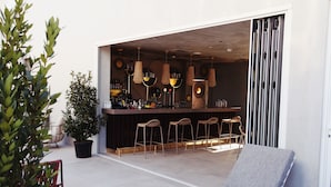 A modern bar area with a seating arrangement, a potted plant, and a lounge chair.