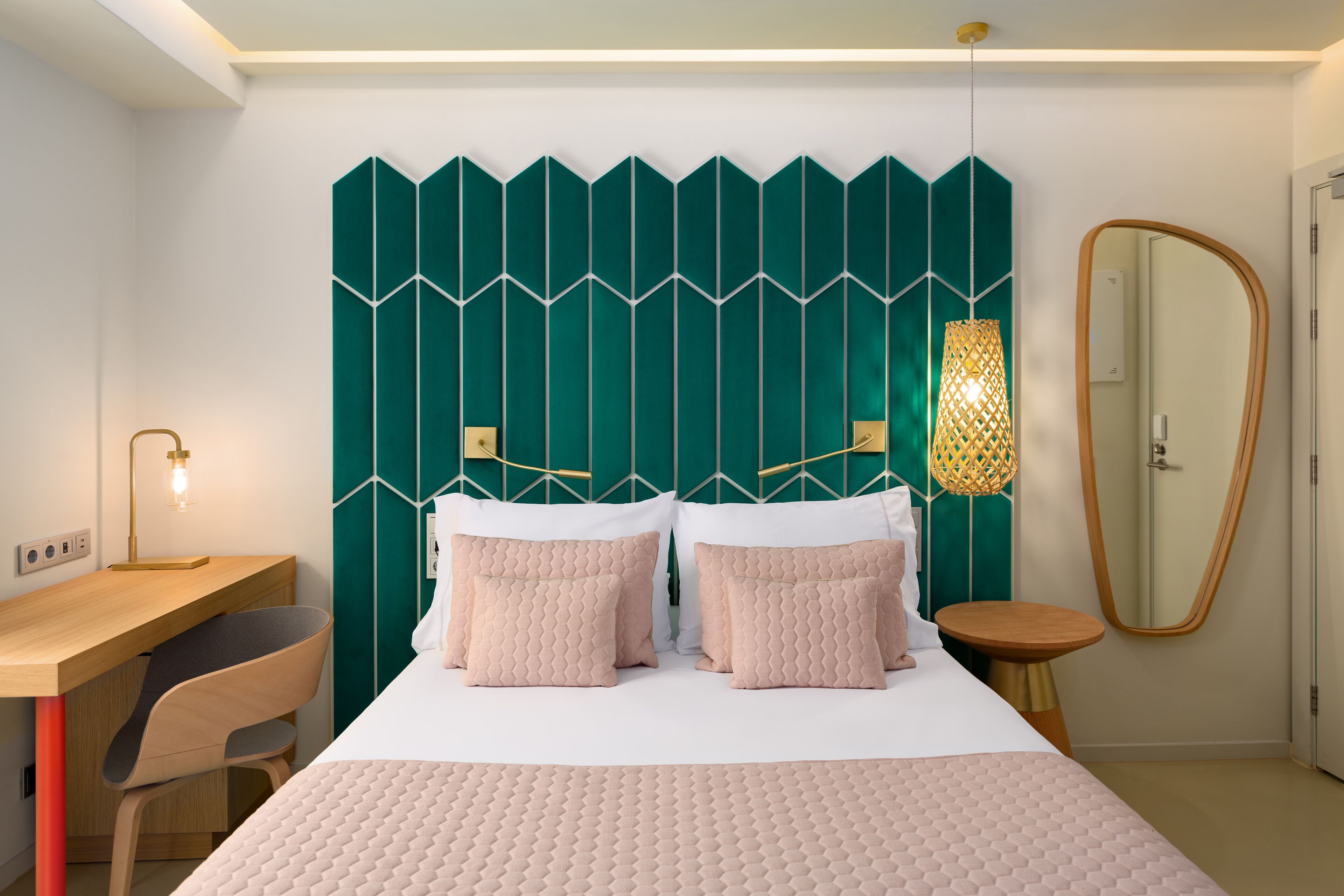Un dormitorio moderno con cama, mesitas de noche, un escritorio y un espejo.