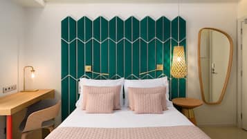 Un dormitorio moderno con cama, mesitas de noche, un escritorio y un espejo.