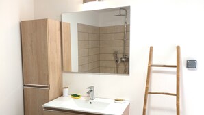 A bathroom with a wooden cabinet, a sink, a mirror, and a shower. - Seasonal rental brand new - 4 pers. -POSSESSION-end construction Oct. 19 (LA POSSESSION)