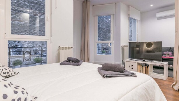 A modern bedroom with a large bed, a TV, and a view of a snowy landscape through the windows.