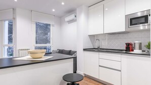 A modern kitchen with white cabinets, a black countertop, and a built-in microwave.