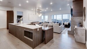 Een moderne keuken met een centraal eiland, ingebouwde apparatuur en een zithoek met een bank en tafel.