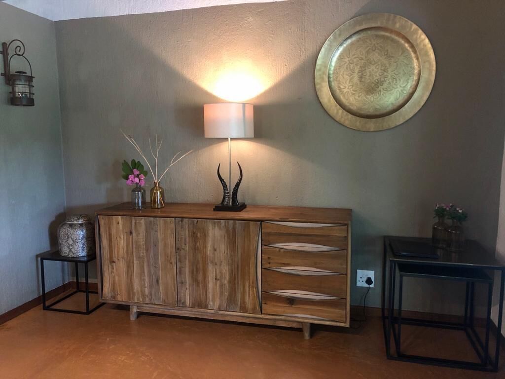 A wooden cabinet with a lamp, a decorative plate, and a vase with flowers.