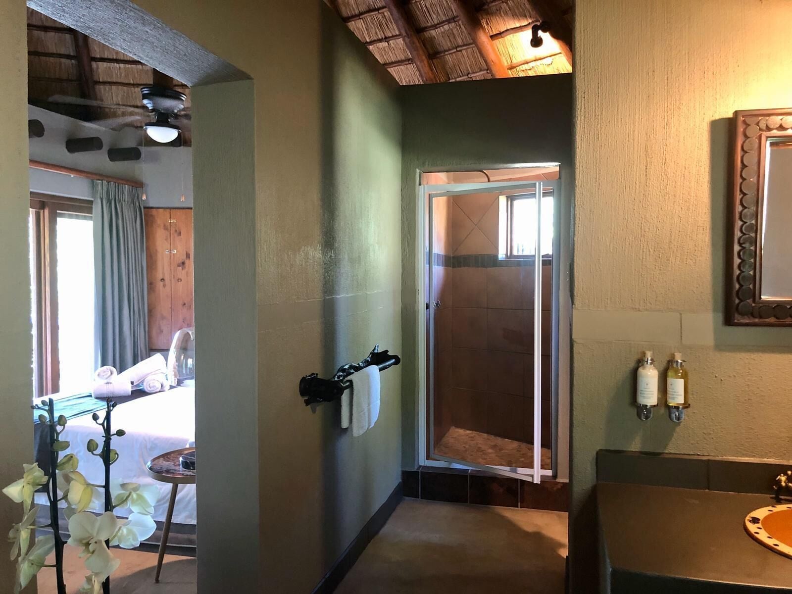 A bathroom with a shower, a sink with a mirror, and a towel rack.