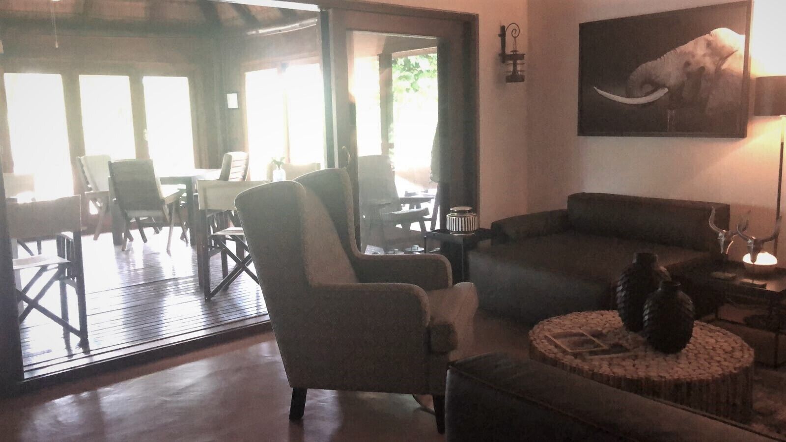 A spacious living area with a large window, a sofa, a chair, and a round coffee table with decorative vases.