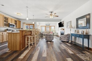 Ein geräumiger Wohnbereich mit Küche, Holzboden und Deckenventilator.