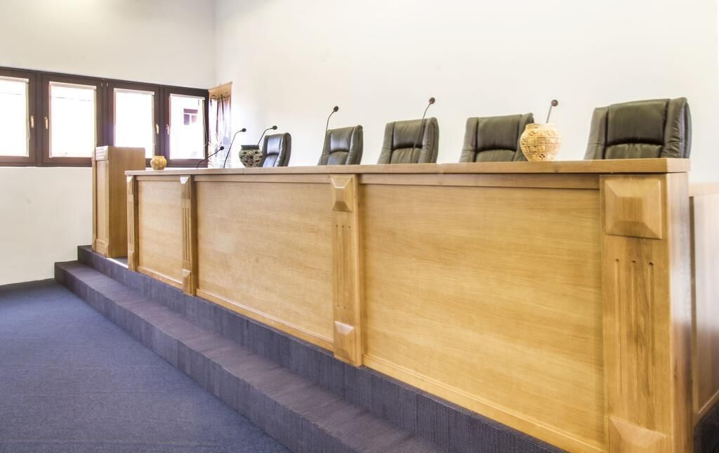 A conference room with a wooden podium, multiple chairs, and a carpeted floor.