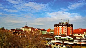 A multi-story building with a red facade and balconies, surrounded by other buildings with varied architectural styles.