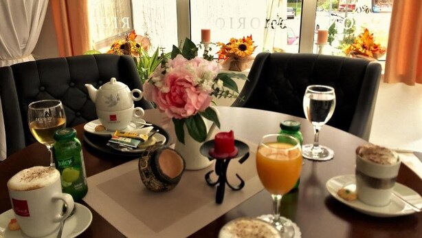 A breakfast setting with a table set for two, including a teapot, cups, a vase with flowers, and various breakfast items. - Hotel Slavonija (Vinkovci)