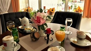 A breakfast setting with a table set for two, including a teapot, cups, a vase with flowers, and various breakfast items. - Hotel Slavonija (Vinkovci)