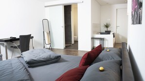 Ein modernes Schlafzimmer mit Bett, Schreibtisch und Spiegel.