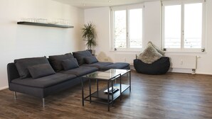 Ein modernes Wohnzimmer mit einer Eckcouch, einem Glastisch und einem schwarzen Sitzsack.