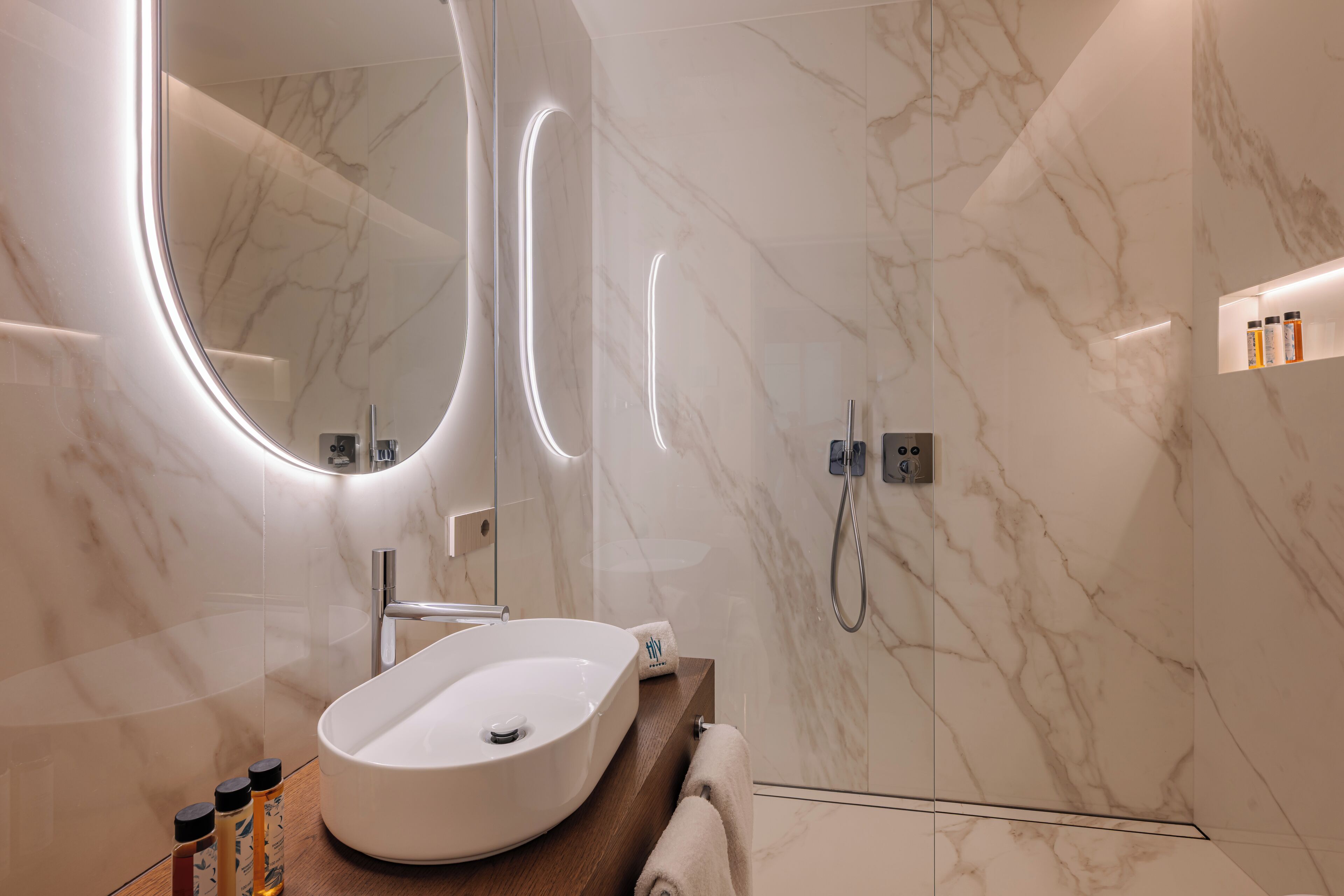 Ein modernes Badezimmer mit einem мрамор Waschbecken, einem großen Spiegel und einer Handbrause.